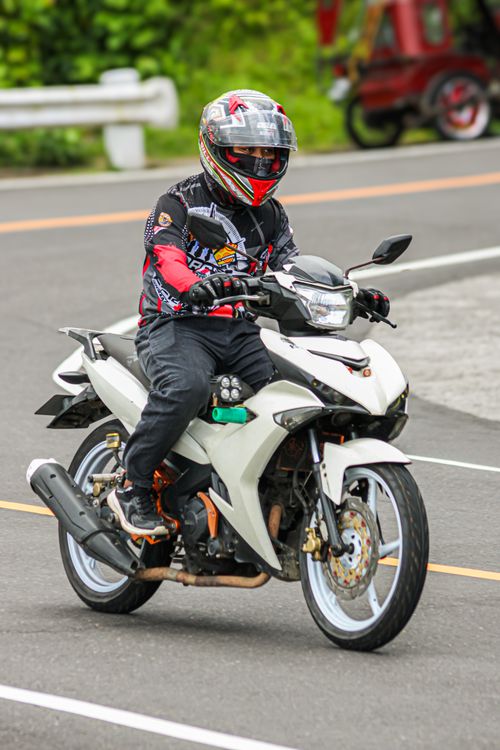 Free Motorcyclist riding with full safety gear on an urban road, showcasing motorcycle and helmet. Stock Photo