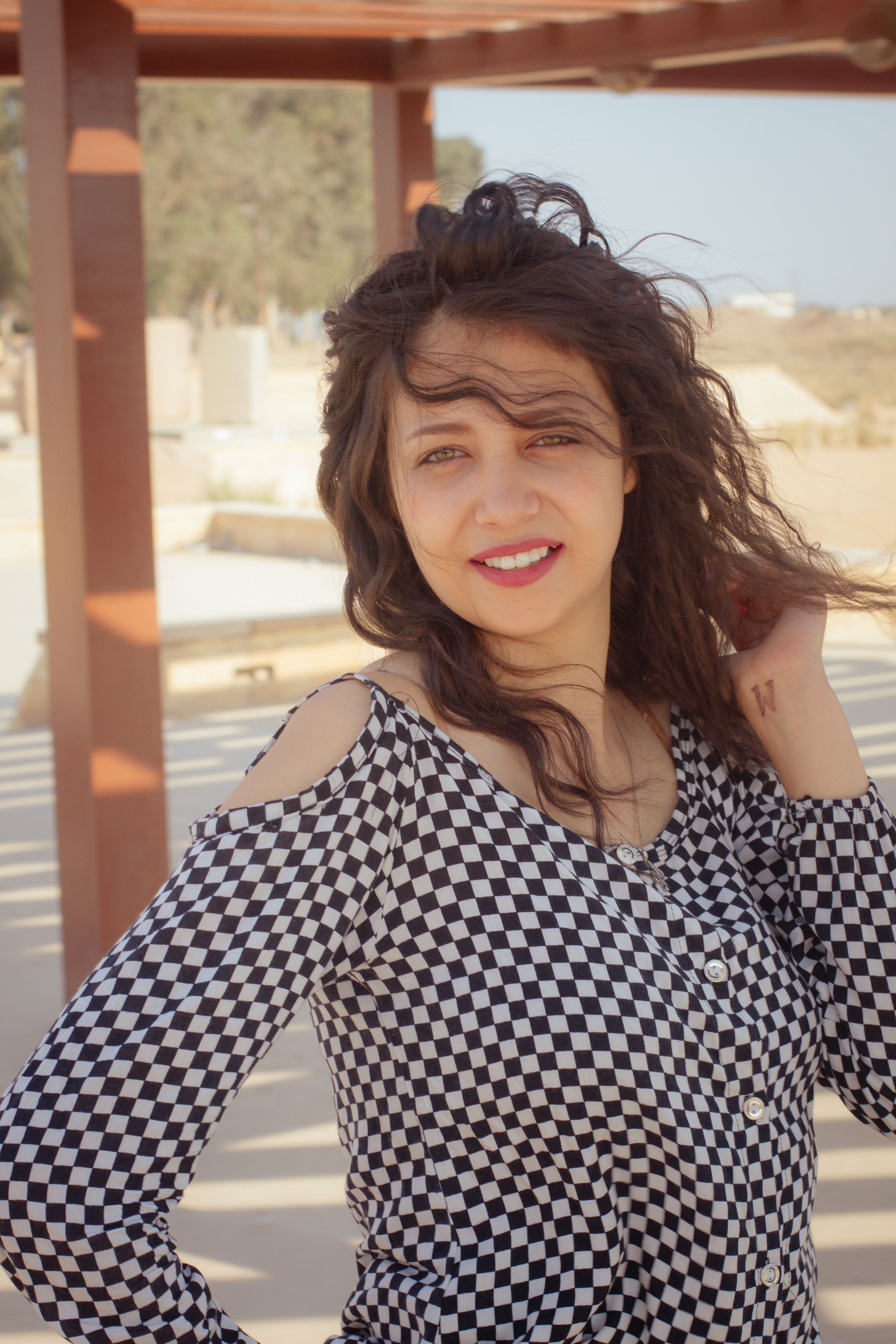 Stylish woman in checkered outfit posing gracefully in Cairo, Egypt's outdoor setting.