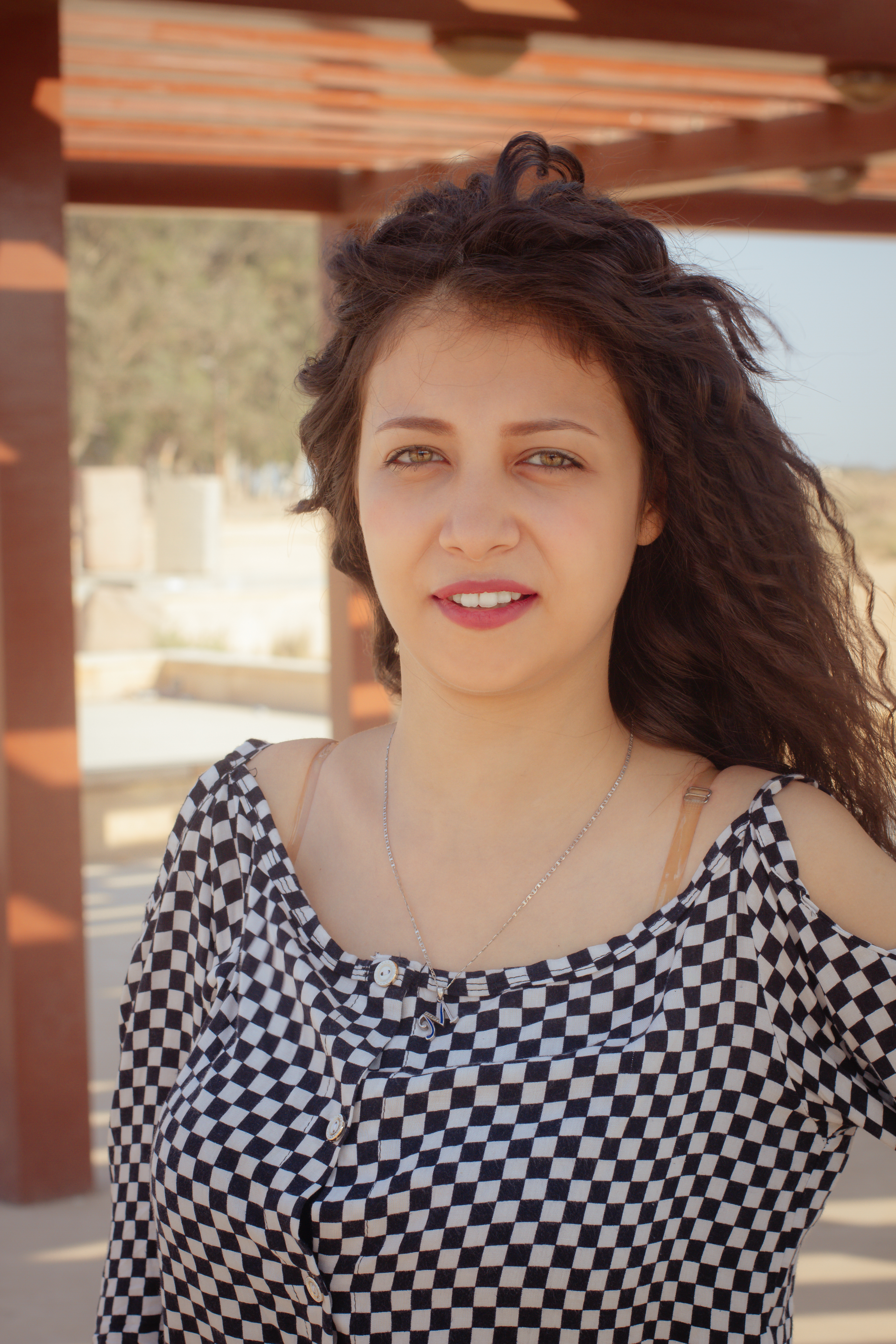 Portrait of a young woman in a checkered blouse, captured outdoors in Cairo, Egypt.