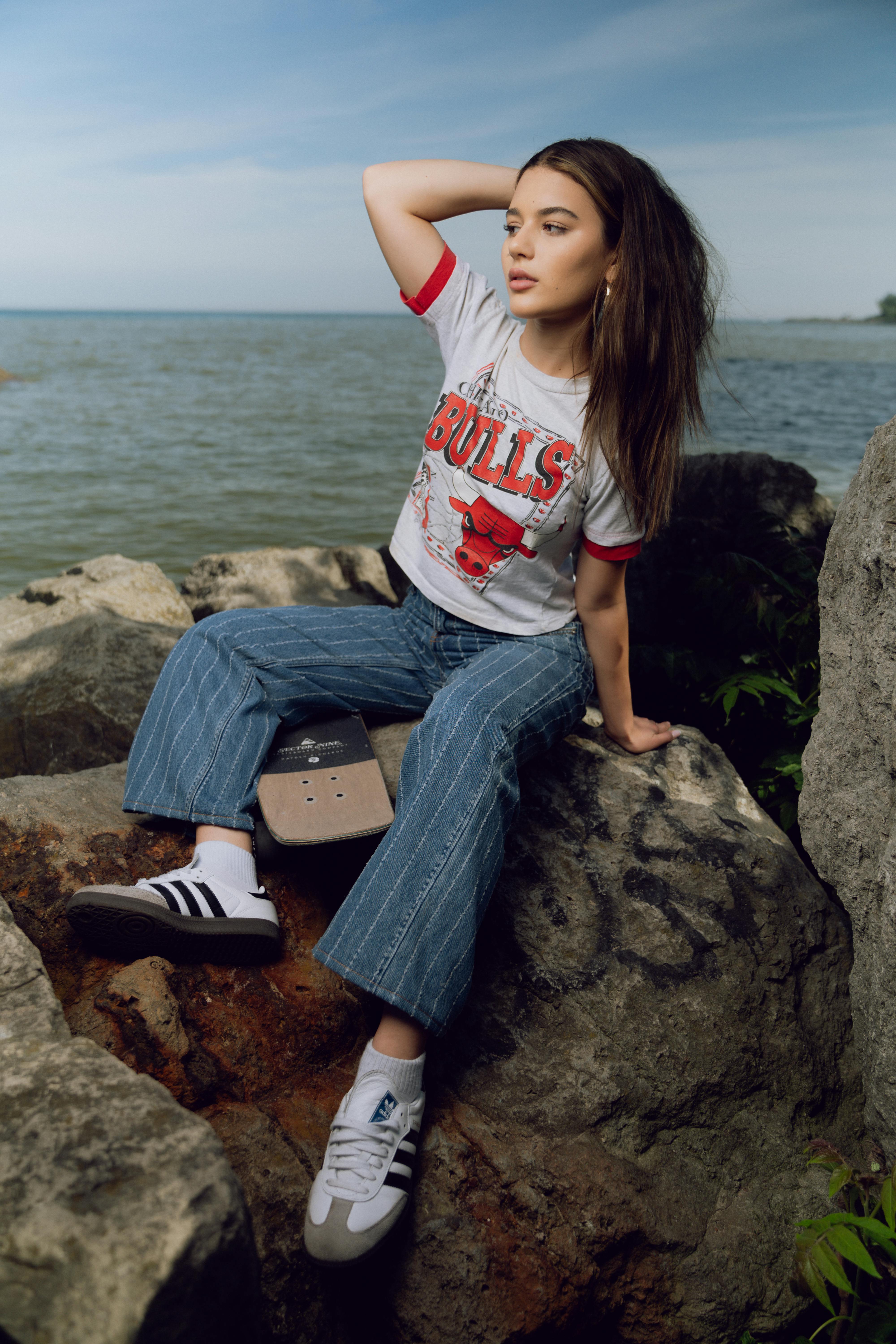 a girl sitting on the rocks by the water