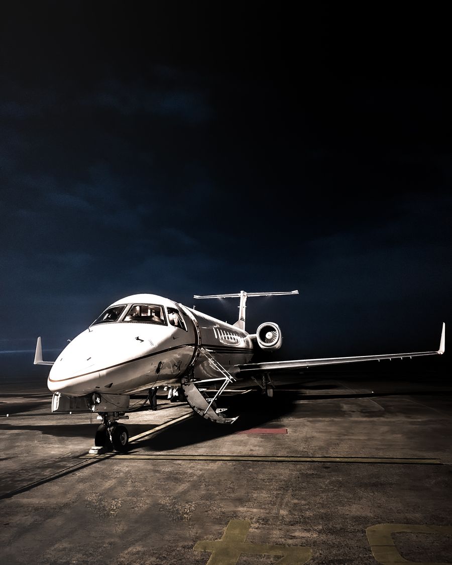 An Embraer Legacy 600 business jet lit on the apron at night in Jakarta, Indonesia