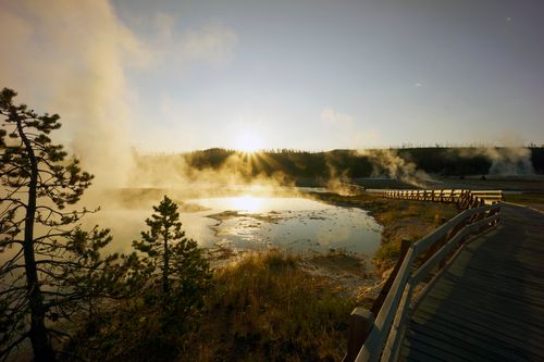 Free Breathtaking sunset view over a steaming geyser basin with boardwalk in Yellowstone National Park. Stock Photo