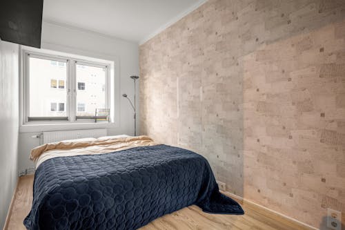A bedroom with a bed and a wall with a wooden floor