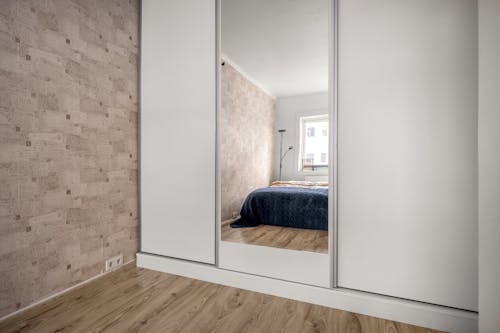 A bedroom with a mirror and wooden floor