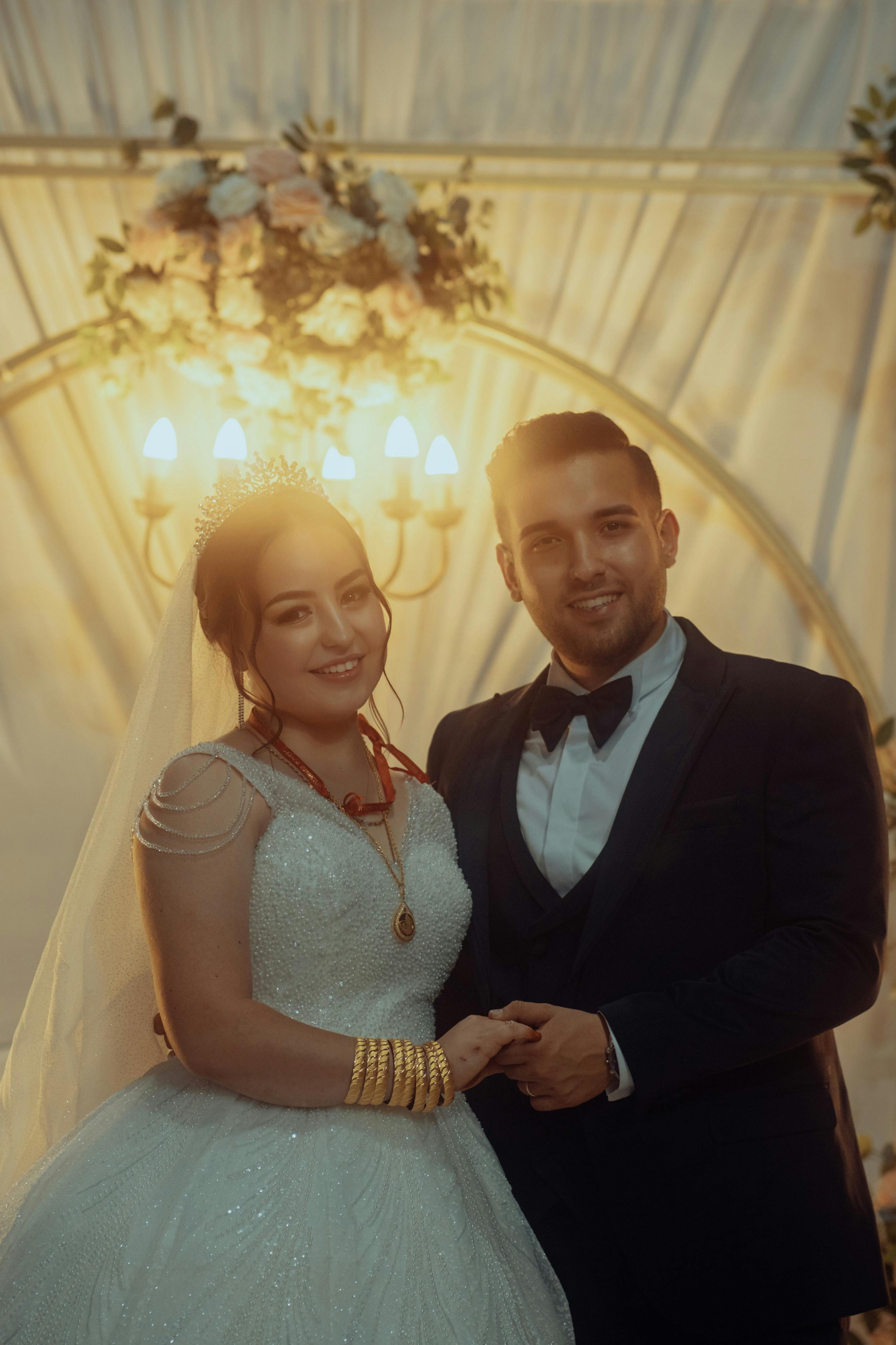 A joyful bride and groom smiling and holding hands at their wedding ceremony.