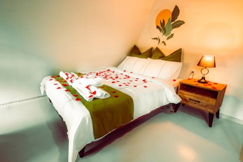 A bed with rose petals on it and a lamp