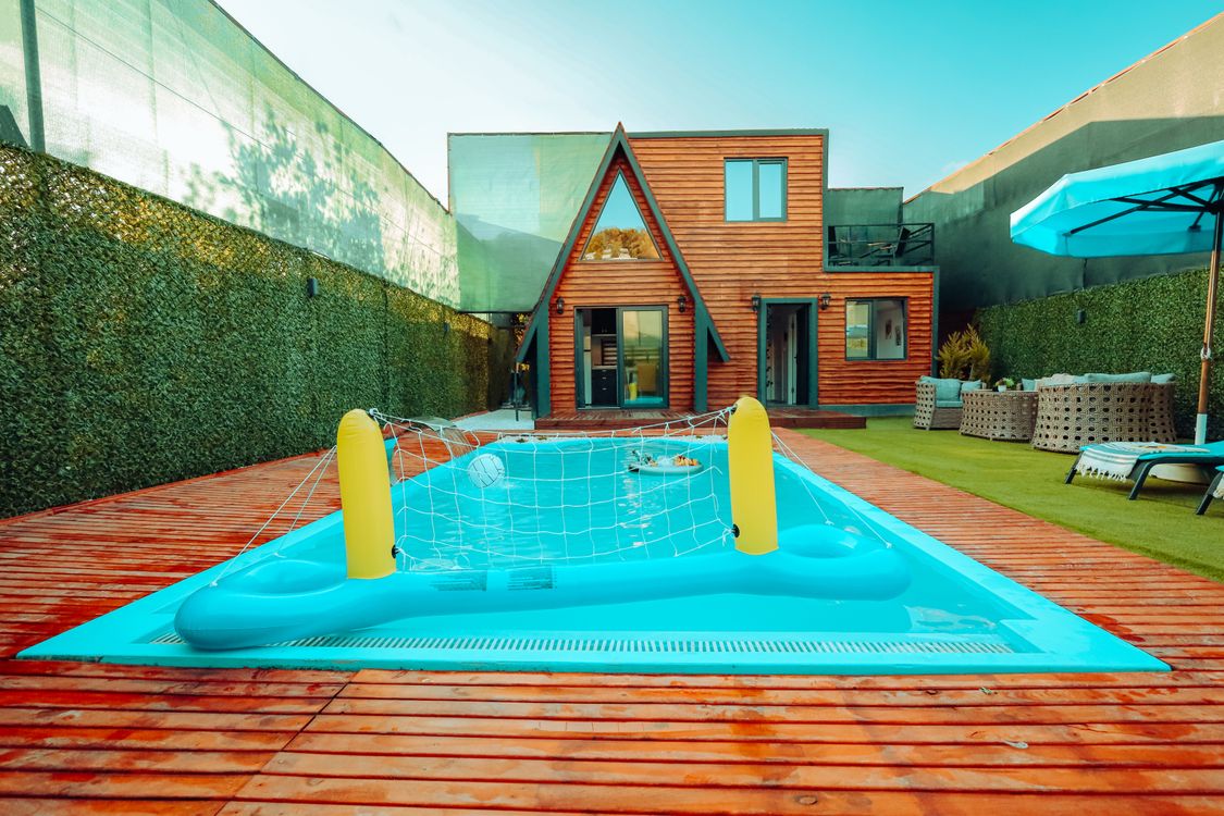 Quintal cercado com piscina, deck de madeira e casa ao fundo