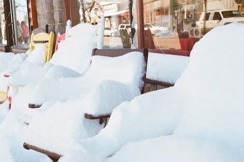 Snow Coated Chairs Beside Clear Glass Storefront