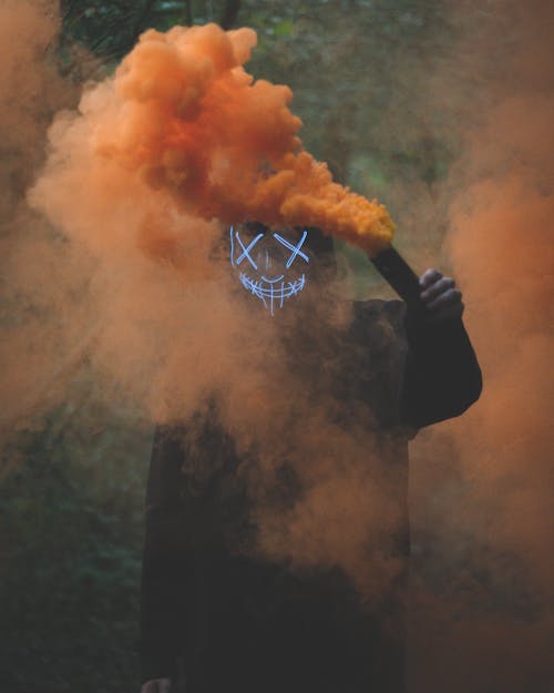 Free Person Wearing Mask Holding Colored Smoke Bomb Stock Photo