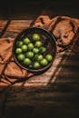 A bowl of limes on a table with a cloth