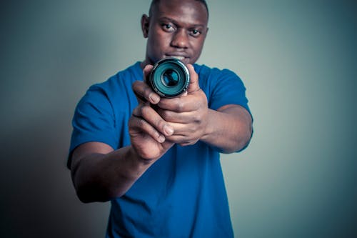 Uomo In Camicia Blu Che Tiene Obiettivo Della Fotocamera