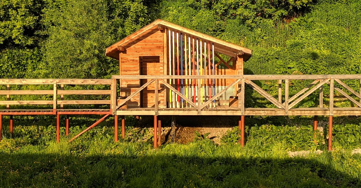 A wooden cabin sits on a wooden bridge over a pond