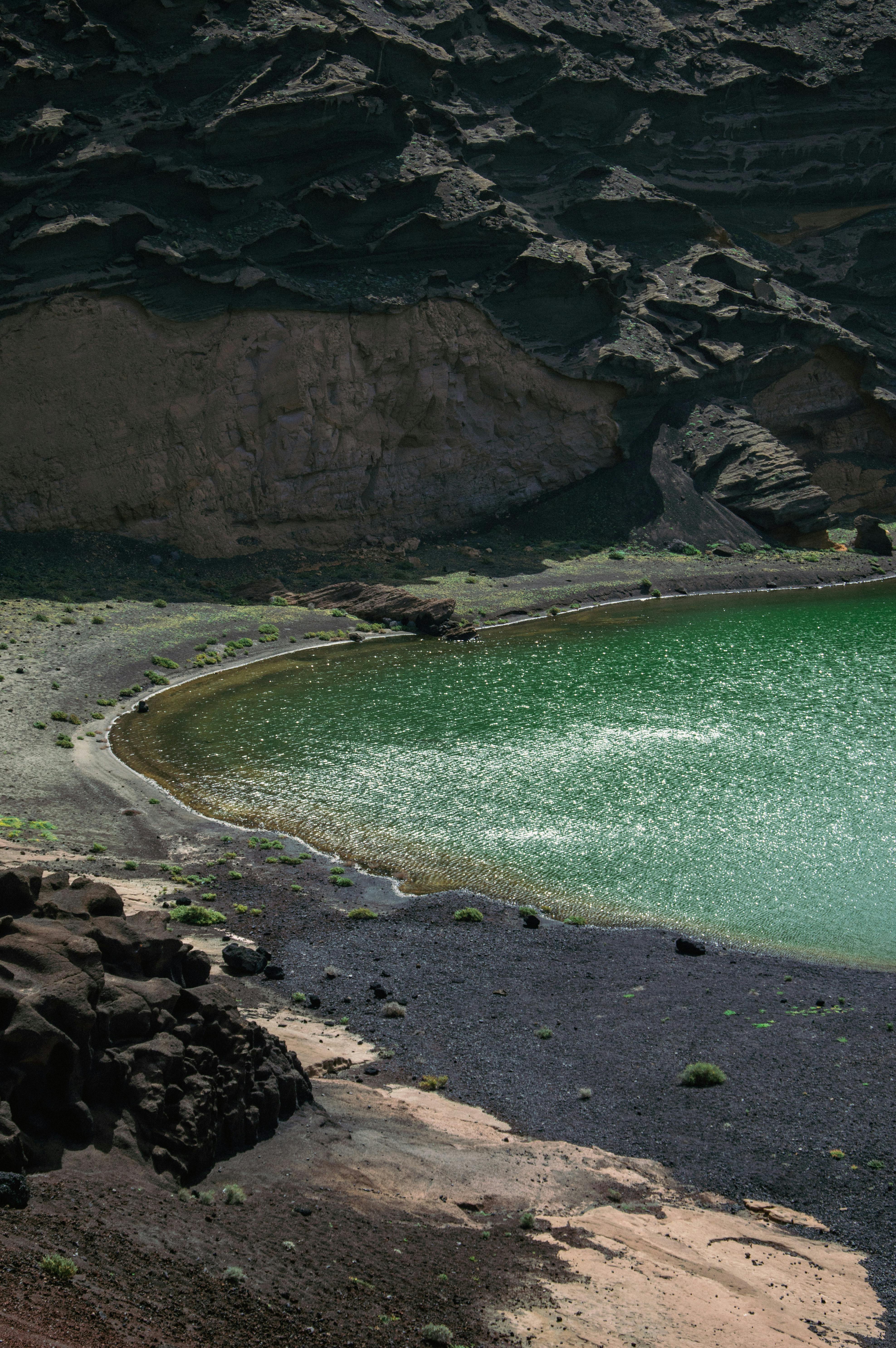 A stunning view of a green lake in Lanzarote's volcanic landscape, highlighting its unique geology.