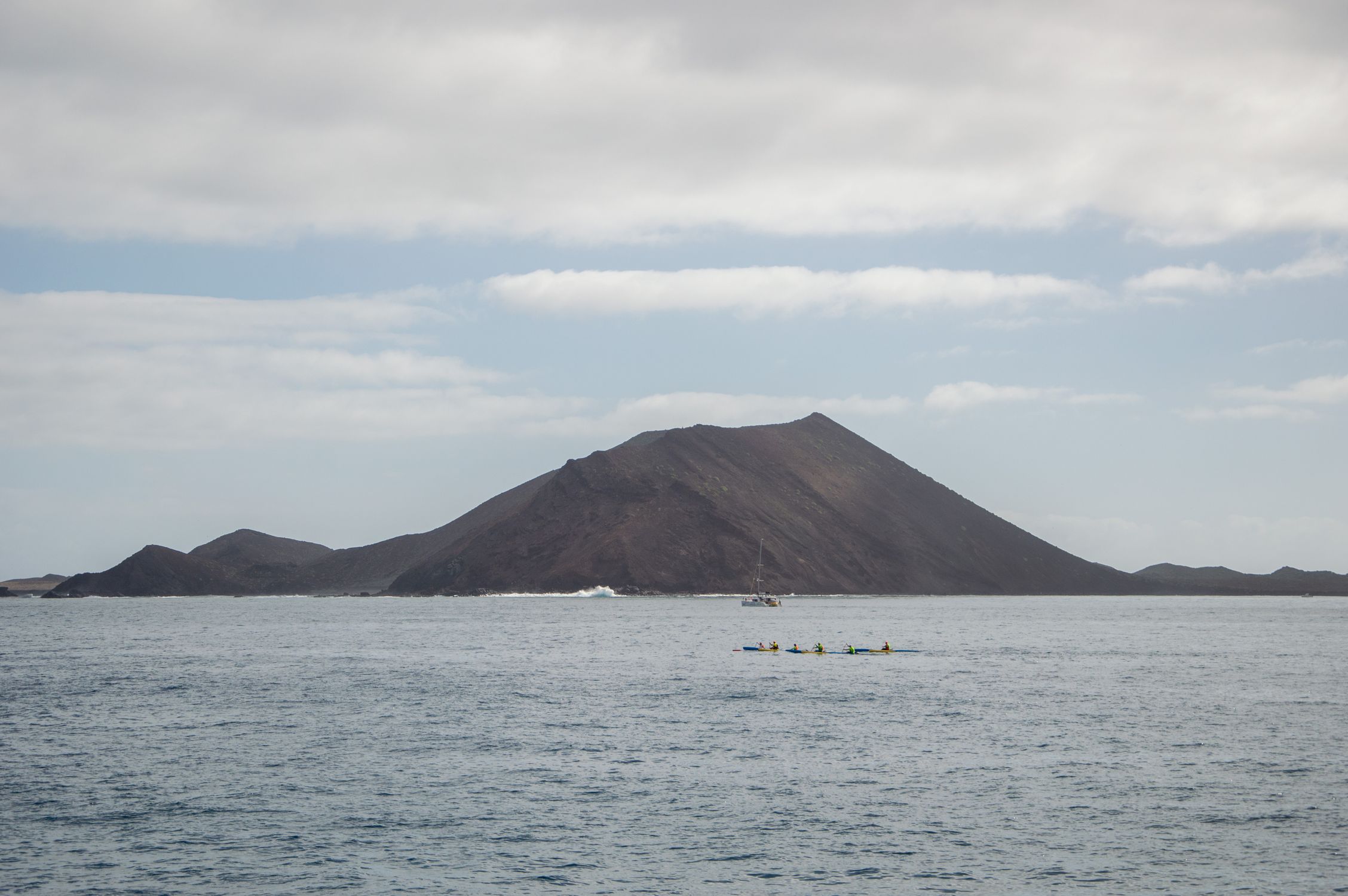 Photographer: lukas-baranauskas Kayakers paddling near a volcanic island coastline in Corralejo, Fuerteventura, Canary Islands