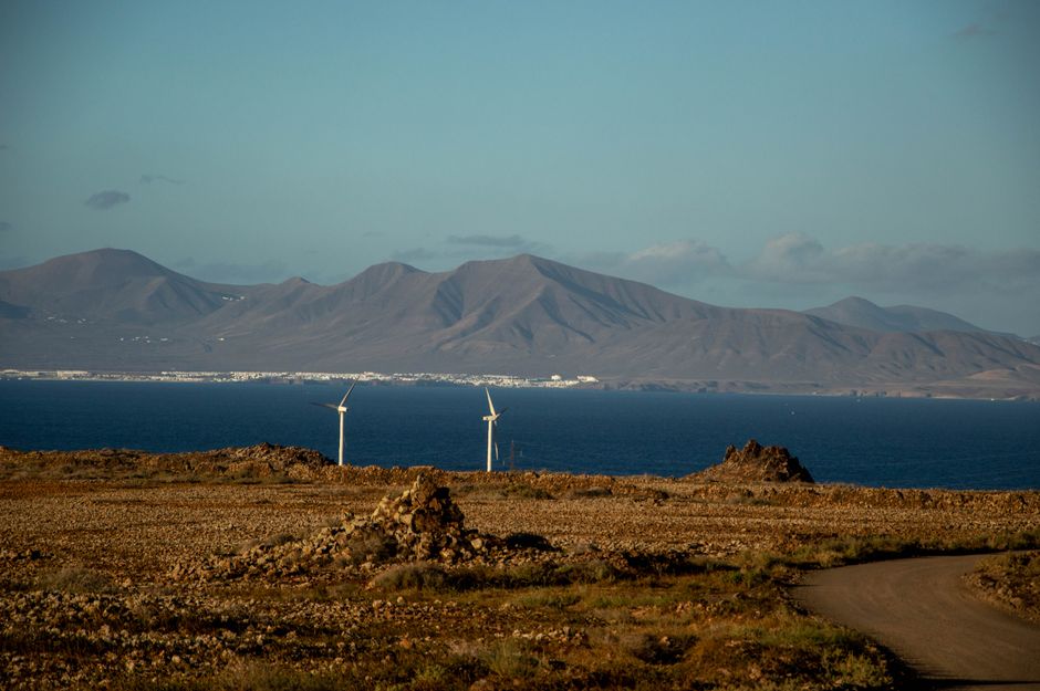 Scenic view of wind turbines and mountains by the coast in Corralejo, Spain.