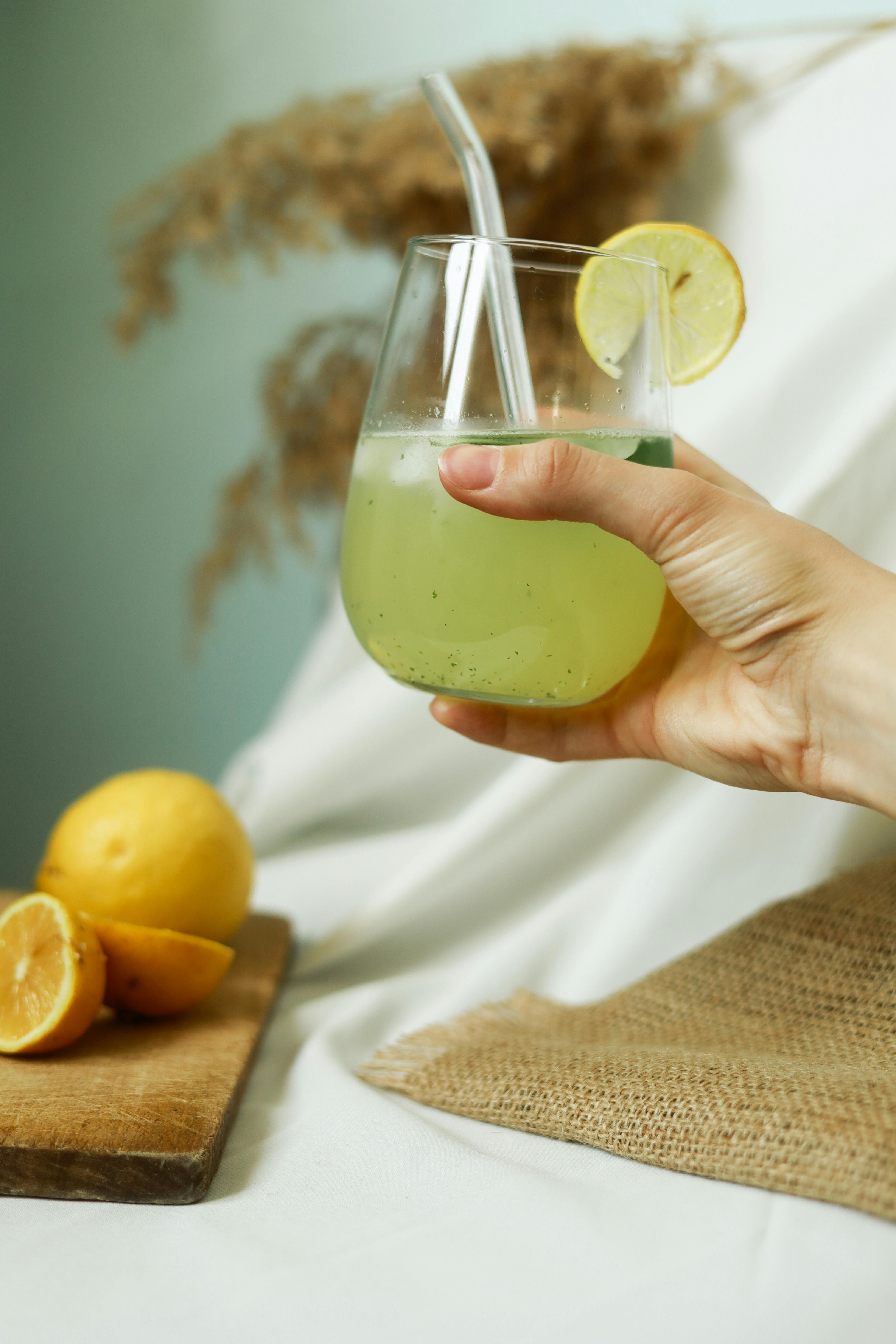 A hand holds a refreshing lemonade glass garnished with lemon slice, capturing summer vibes.