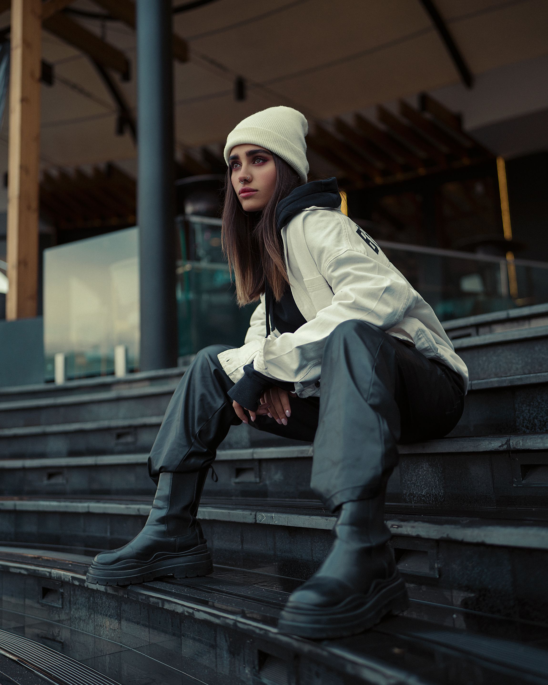 Jovem mulher moderna em streetwear urbano posa nos degraus da cidade.