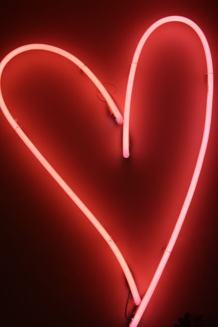 A glowing pink neon heart sign symbolizing love and romance in Lisbon's vibrant nightlife.