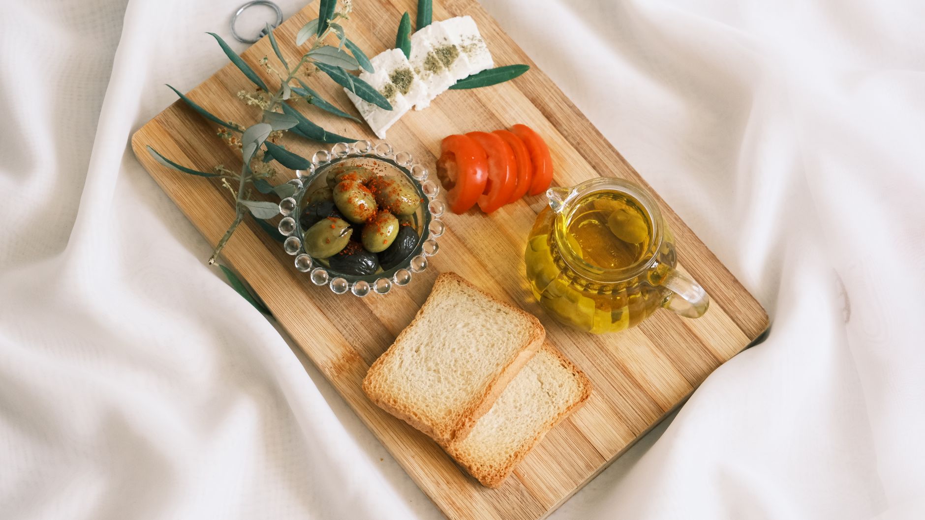 A delicious assortment of olives, cheese, tomatoes, and bread arranged on a wooden board.