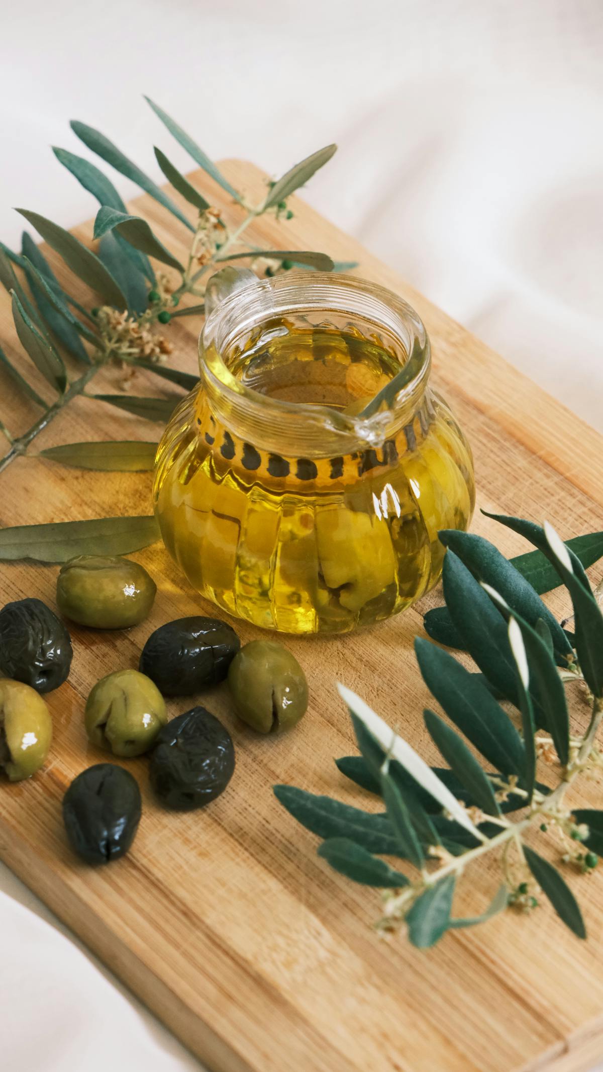 Barattolo di olio d'oliva su tagliere di legno con olive