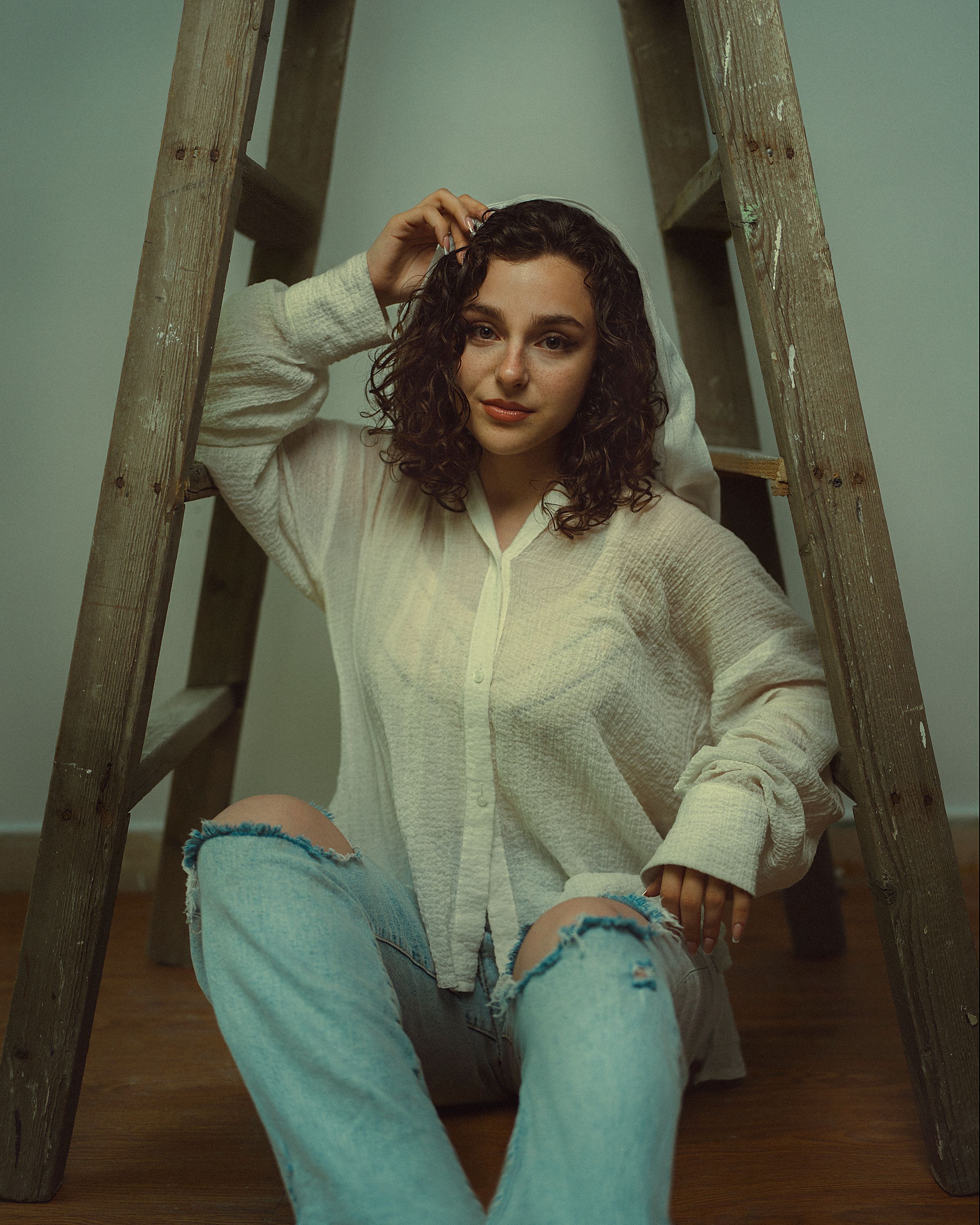 A Woman in a White Shirt and Ripped Jeans Sitting under a Ladder · Free ...