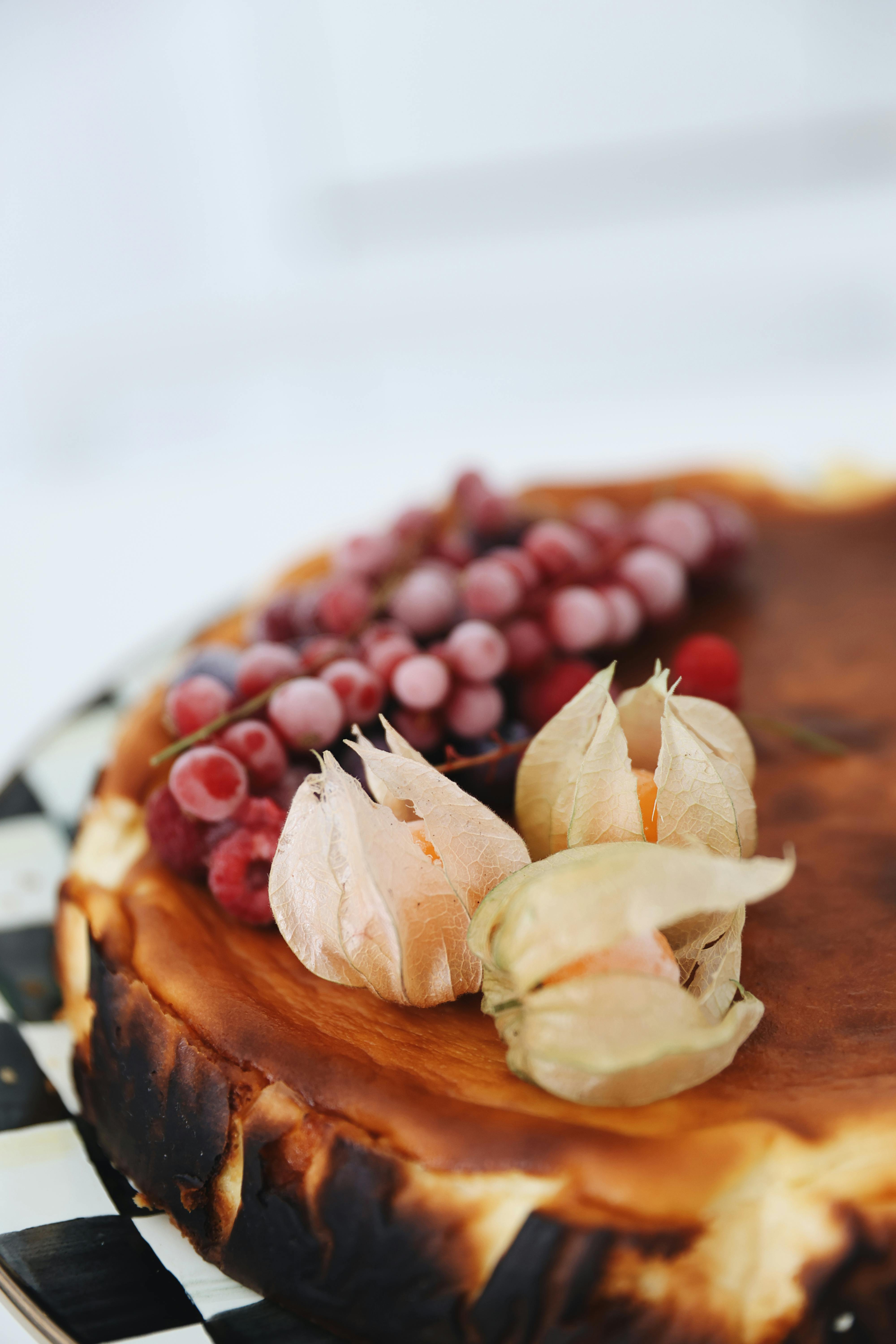 Creamy Basque cheesecake topped with fresh grapes and gooseberries on a tray.
