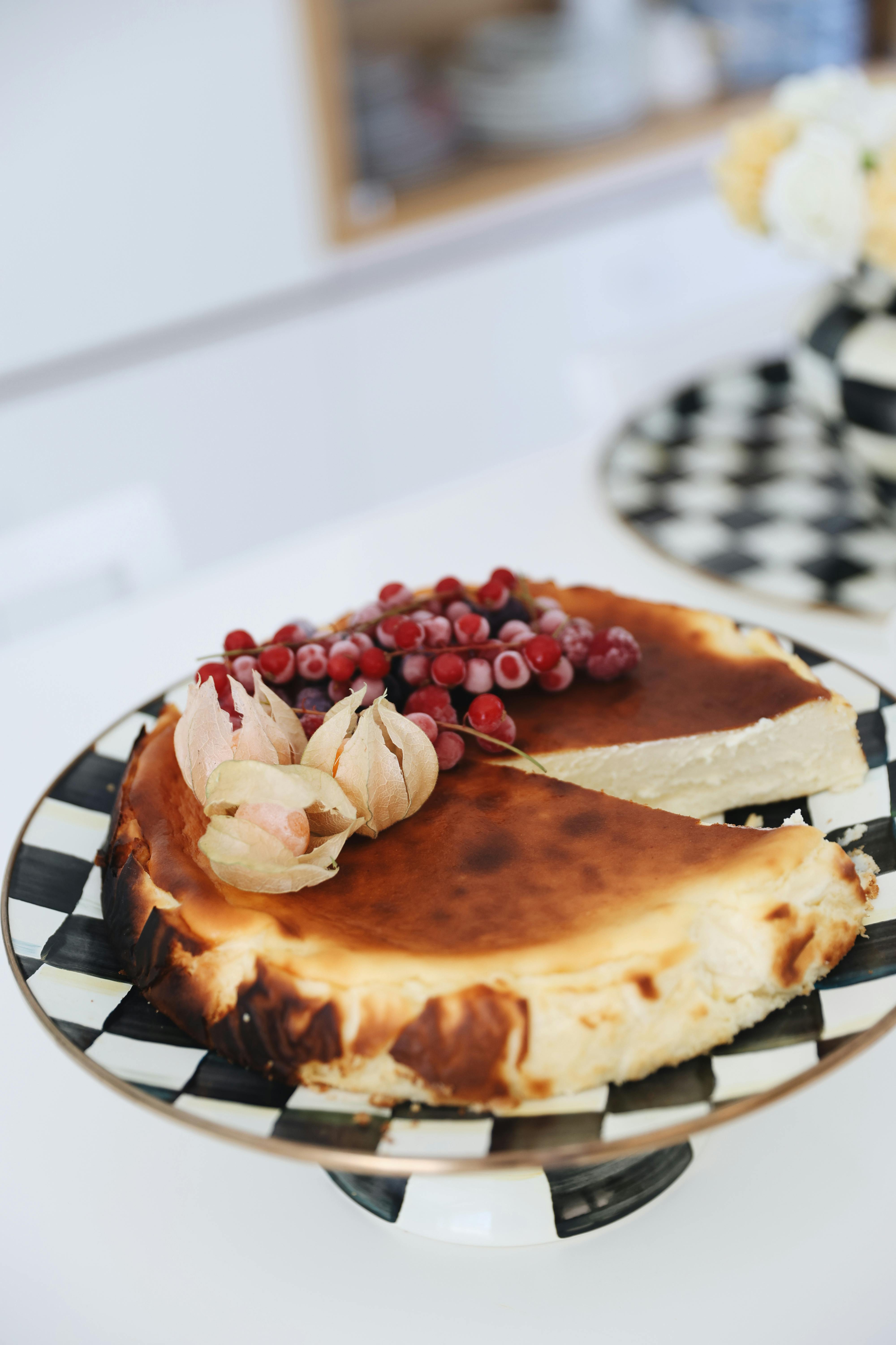 Indulge in creamy cheesecake topped with vibrant fruits, served on a stylish checkered plate.