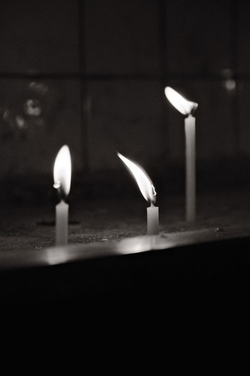 Free Three lit candles creating a serene and dramatic atmosphere in black and white. Stock Photo