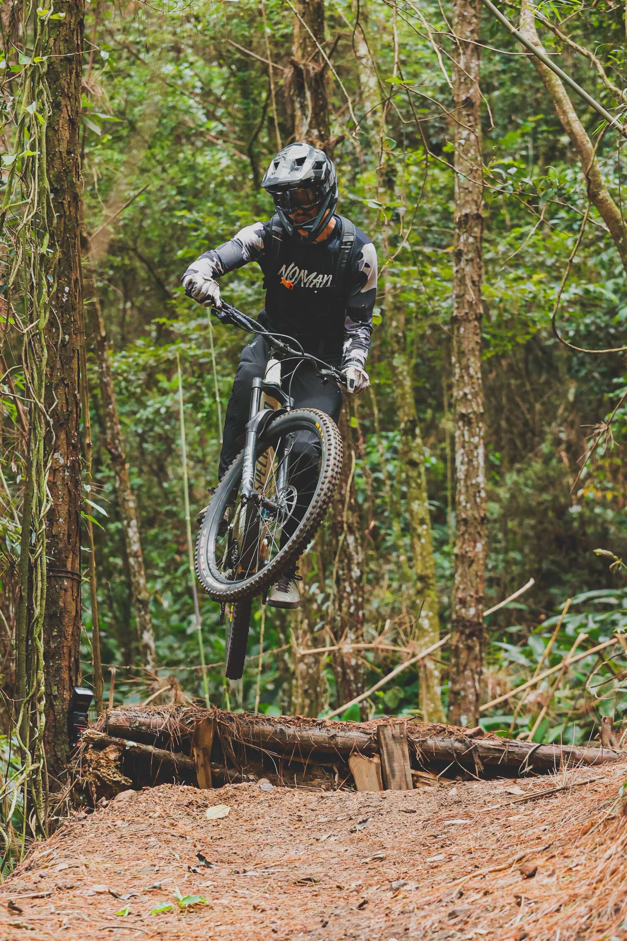Dynamic shot of a mountain biker performing a jump on a forest trail.