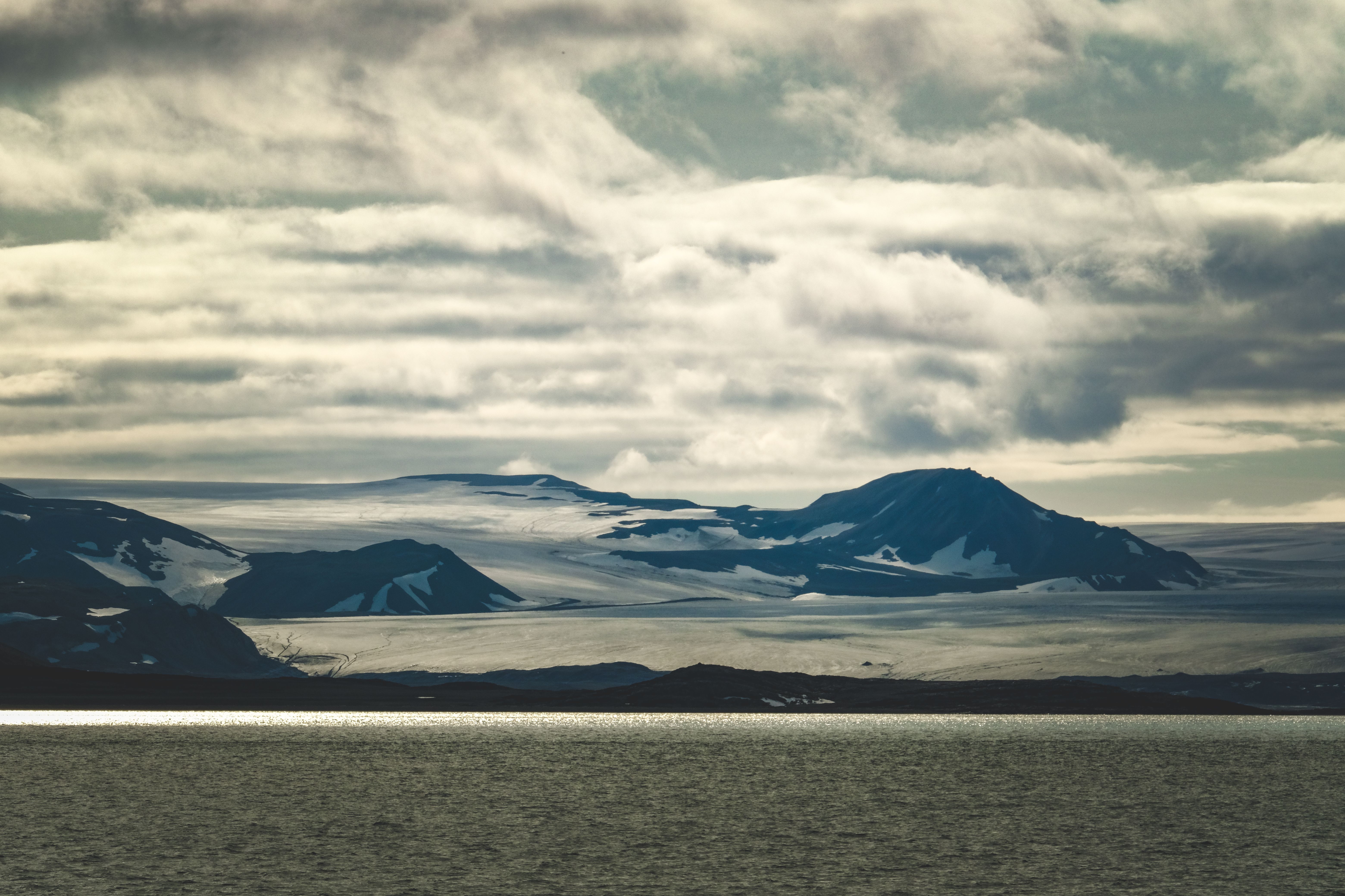 A stunning view of a glacier meeting the sea under dramatic clouds.