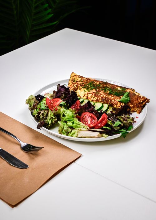 Free Delicious omelette paired with fresh salad and tomatoes on a white table setup. Stock Photo