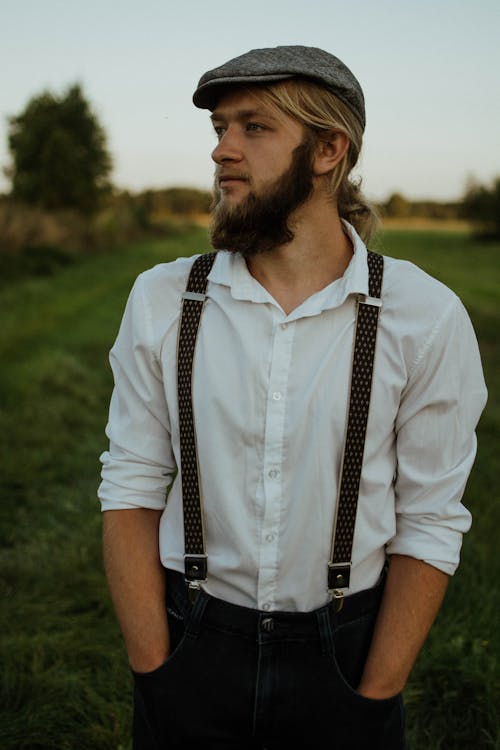 A man with a beard and suspenders in a field