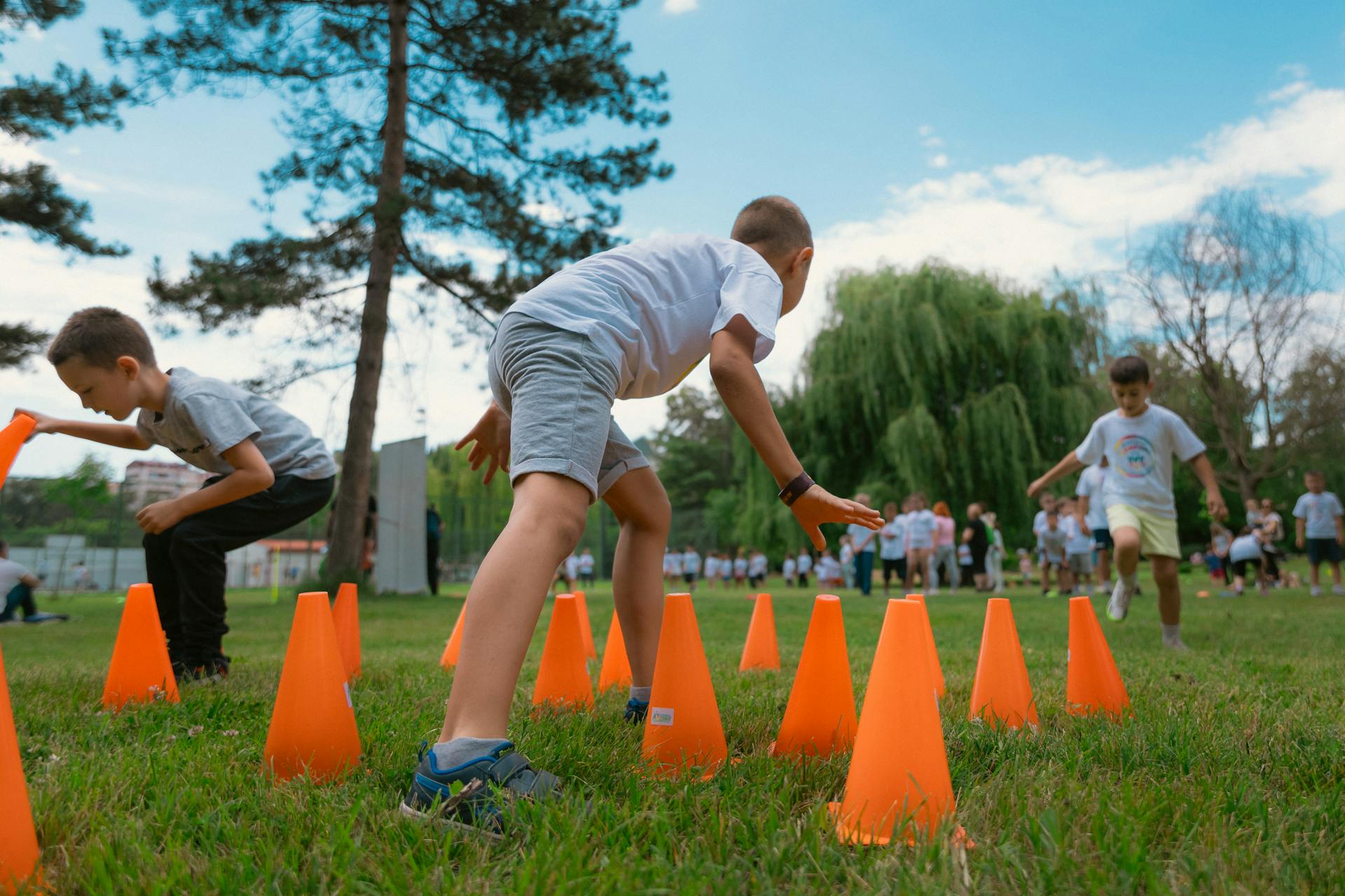 Children Placing Obstacle Course Cones on Grass