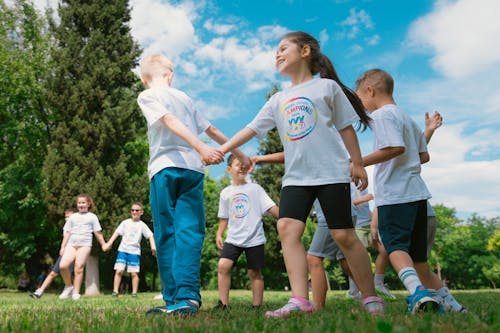 Children in white shirts and blue shorts holding hands