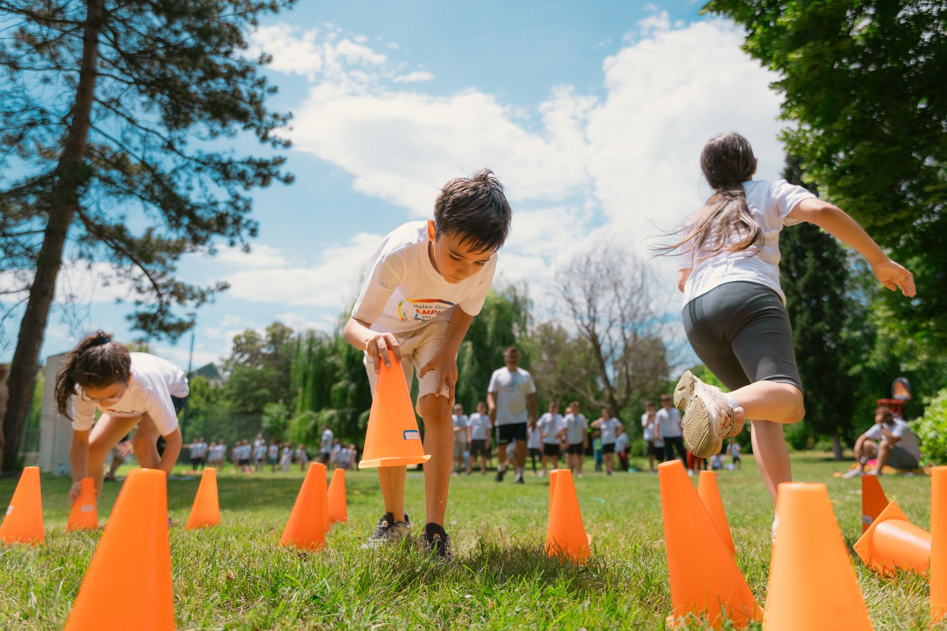 Children playing an obstacle course in a park on a sunny day, promoting fun and physical fitness.