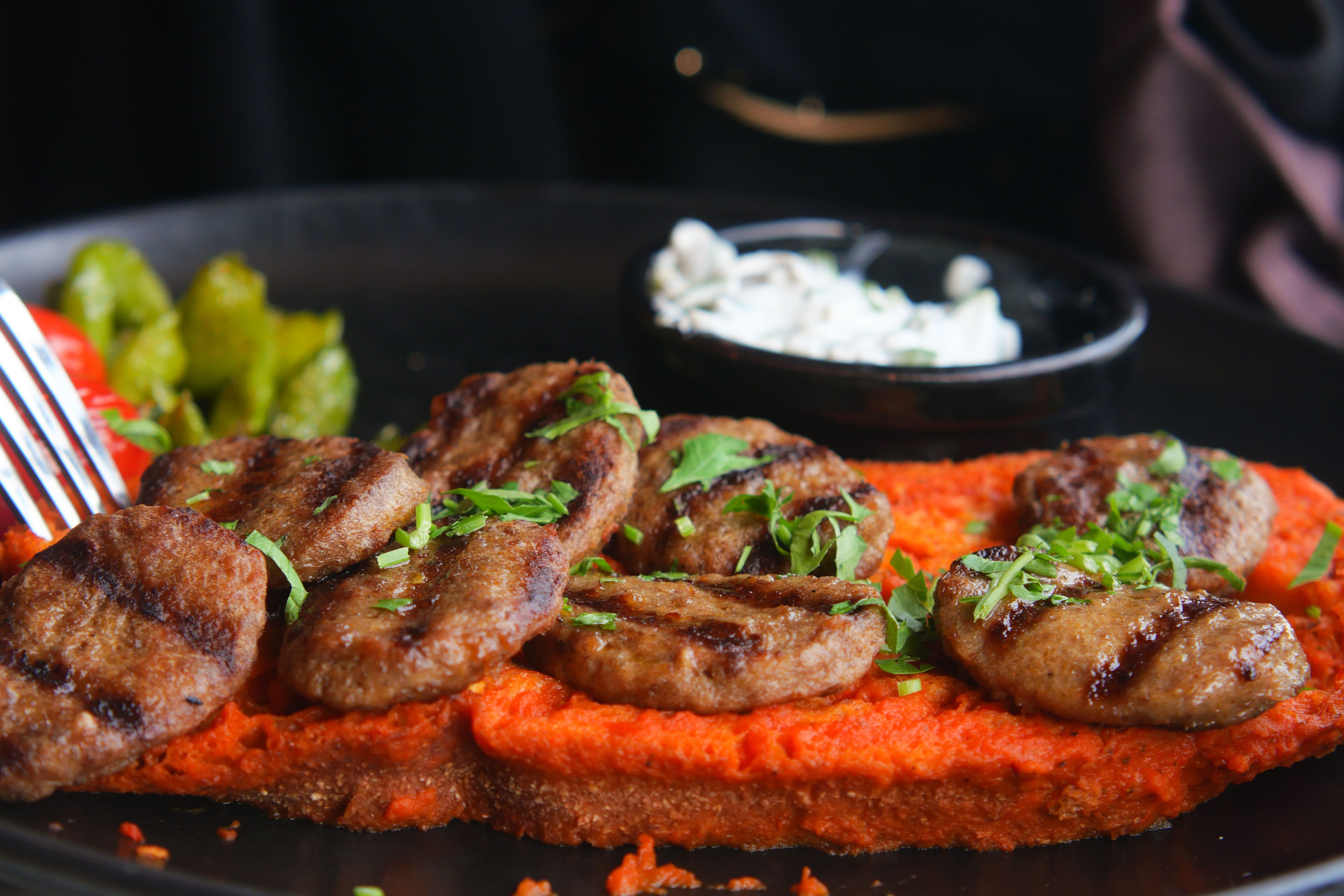 A plate of grilled ćevapi with kajmak and chopped onions, a classic Serbian dish.