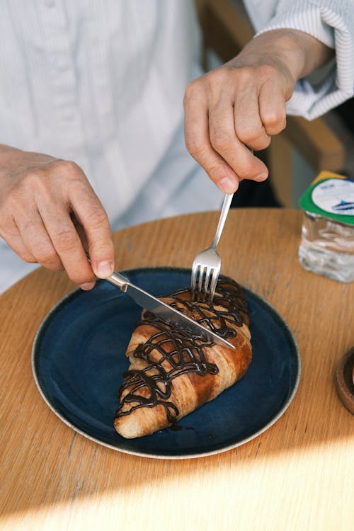 A person cutting a piece of bread with a knife