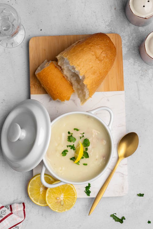 A bowl of soup with bread and lemon slices