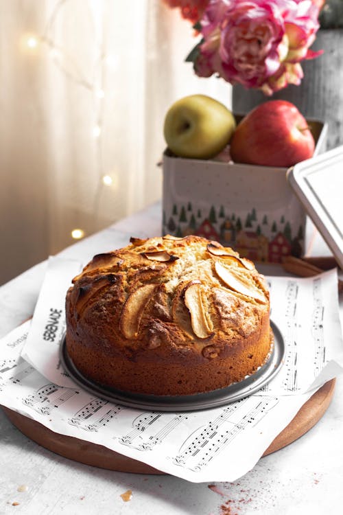 A cake with apples on top sits on a plate