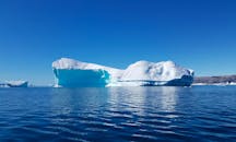 在蔚蓝的天空下，一座巨大的冰山漂浮在格陵兰岛蒂尼特基拉克的原始水域