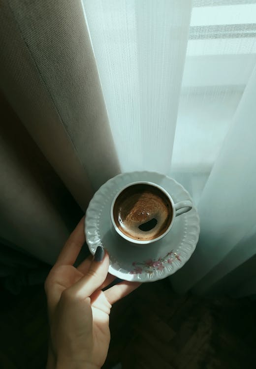 Holding a Porcelain Cup of Coffee on a Saucer