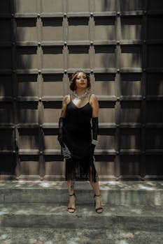 Stylish woman in a black dress poses in front of a textured wall in Mexico City.