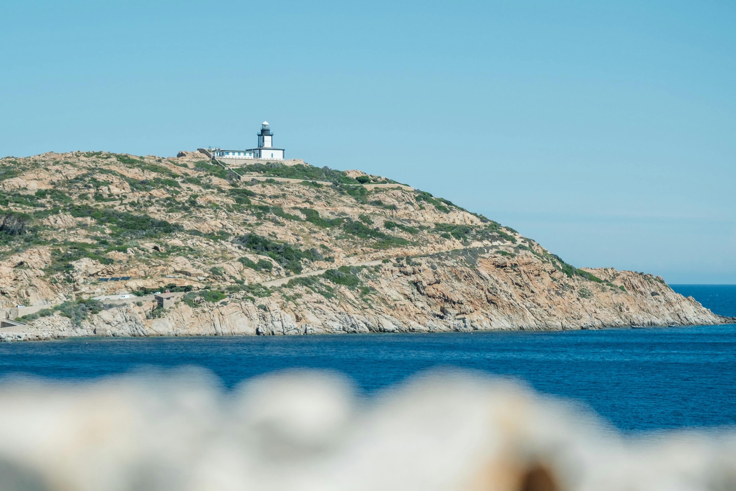 Stunning view of lighthouse on rocky hill overlooking the sea in Calvi, Corsica.