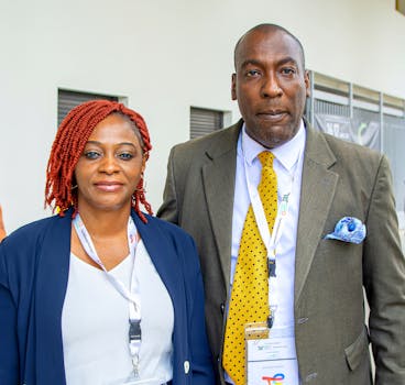 Portrait of two professionals attending a business conference, showcasing formal attire and identification badges.