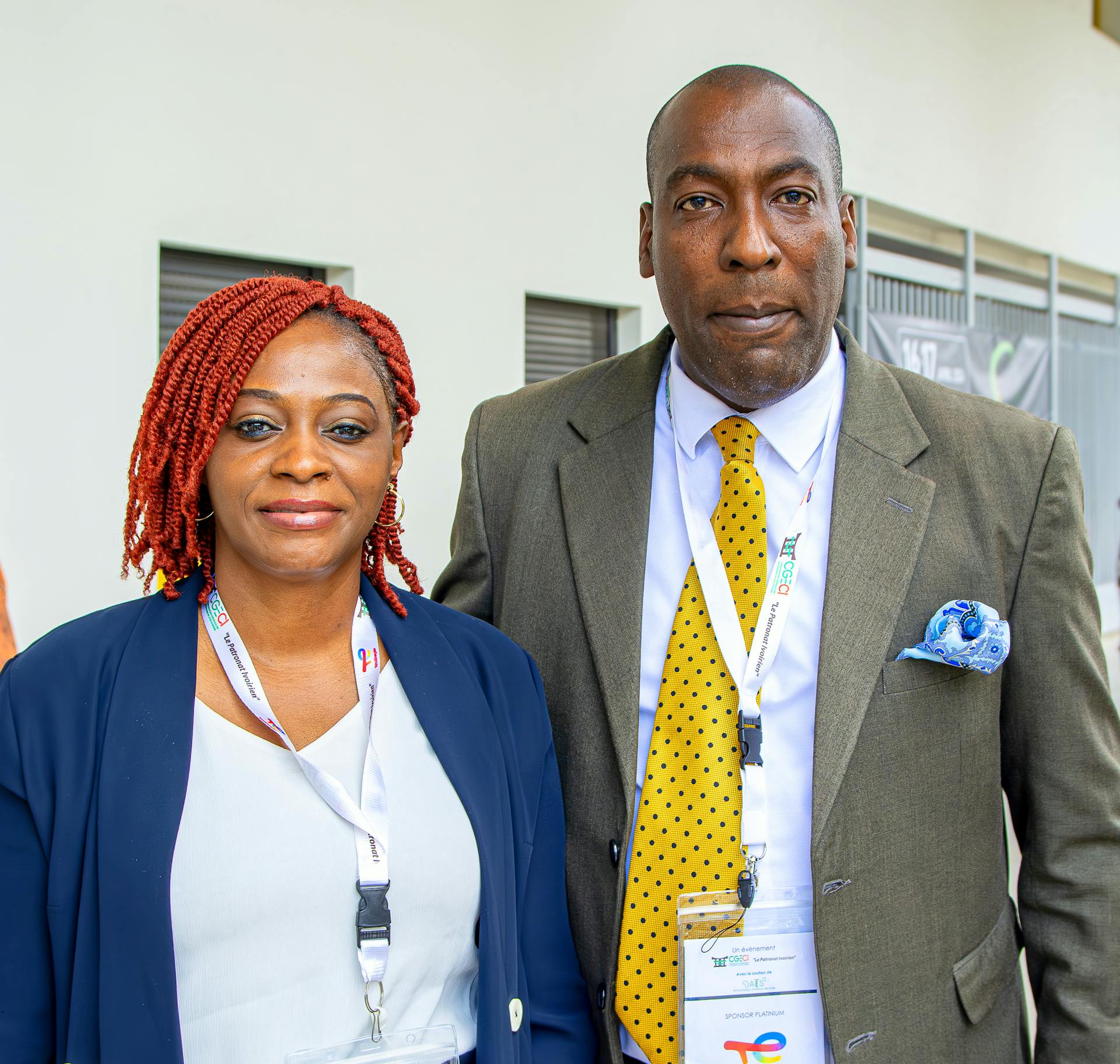 Portrait of two professionals attending a business conference, showcasing formal attire and identification badges.