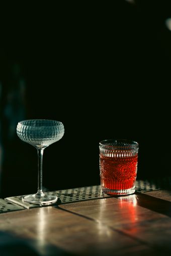 Ribbed glass tumbler and coupe on a dark table — photo by Kunal Lakhotia on Pexels