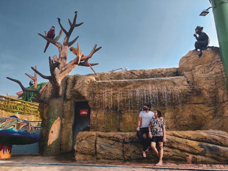 一对夫妇在风景优美的公园里欣赏着动物雕塑和人造瀑布