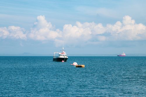 Free Peaceful seascape with motorboats, buoys, and clouds near the coast of Wales. Stock Photo