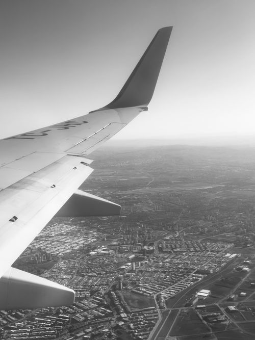 Free Monochrome view of suburban landscape seen from an airplane, showcasing urban sprawl and wing detail. Stock Photo