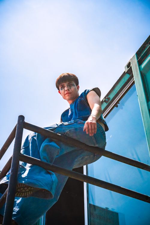 Free Portrait of a young man sitting on a railing with blue sky background in San Pedro Cholula, Mexico. Stock Photo